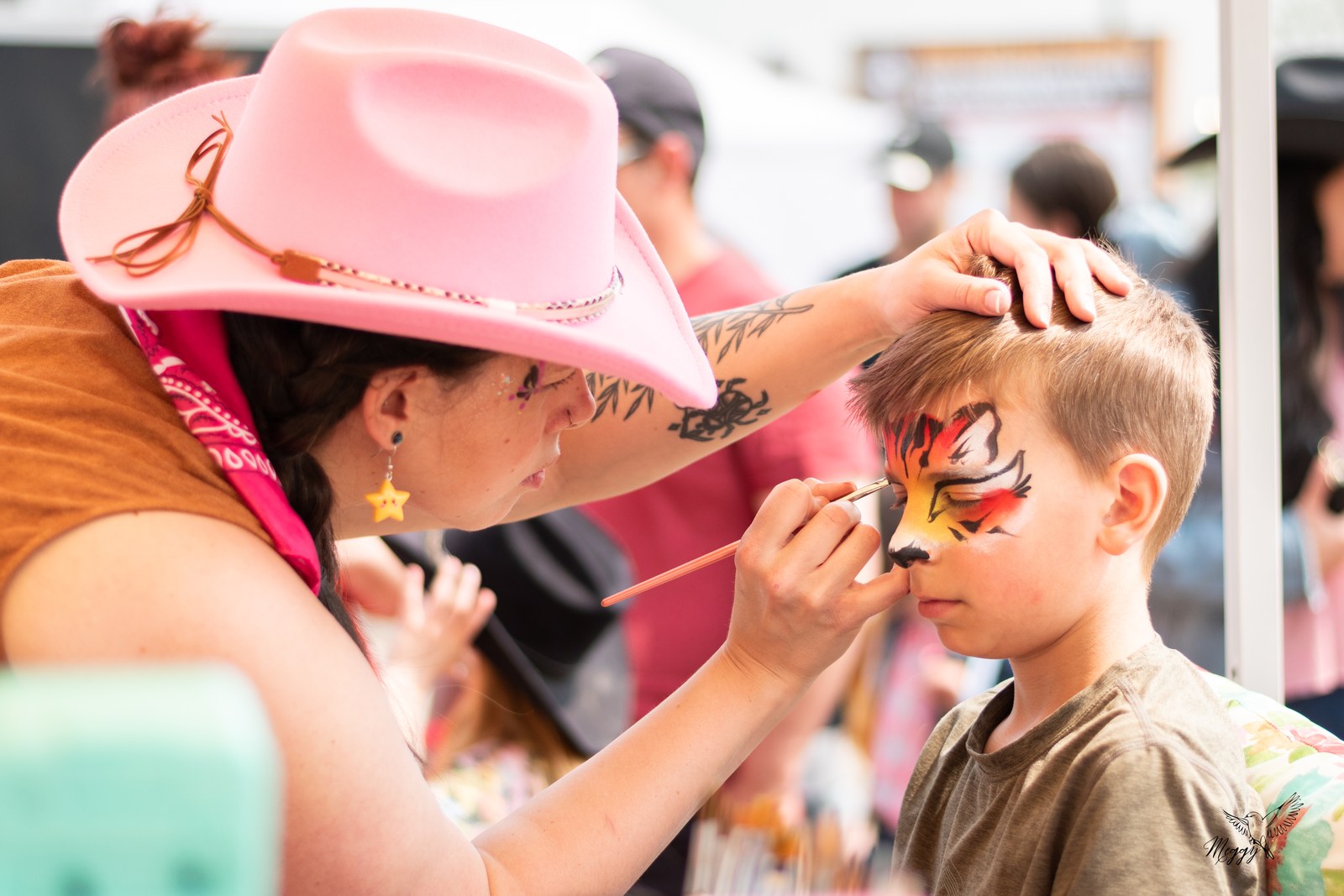 Une maquilleuse réalise un maquillage coloré sur le visage d’un enfant au Festival.
