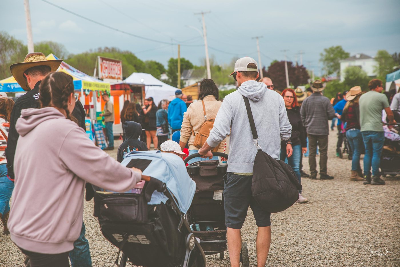 Des familles parcourent l’allée des comptoirs et kiosques du Festival.