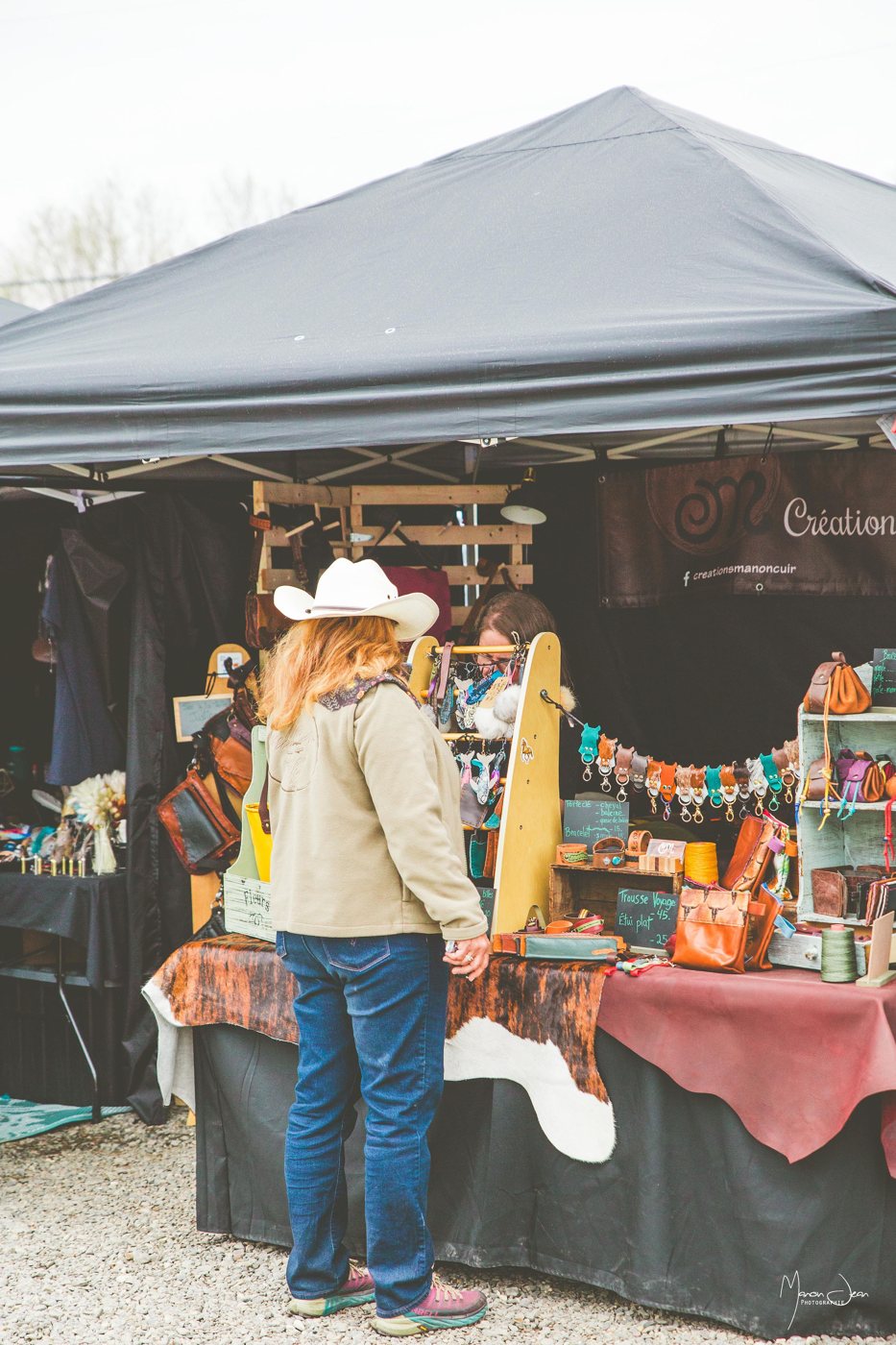 Une visiteuse découvre les créations et accessoires proposés dans un kiosque.
